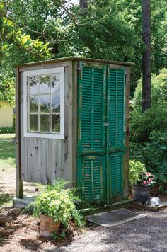 an outhouse in the woods with green shutters