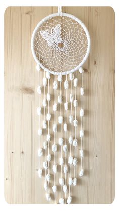 a white beaded dream catcher hanging on a wooden wall