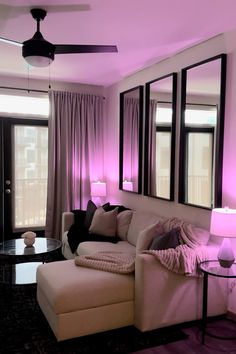 a living room filled with furniture and purple lighting on the wall above it's windows