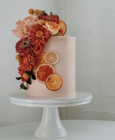 a pink cake decorated with oranges and flowers