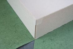 an open box sitting on top of a green tablecloth covered floor with a black piece of tape