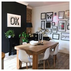 a dining room table with white chairs and pictures on the wall