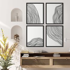 three black and white paintings hanging on the wall above a wooden table with vases