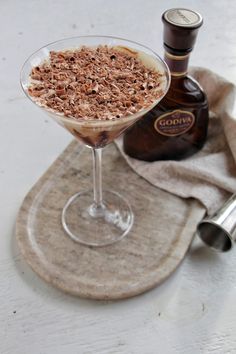 a drink in a martini glass with chocolate shavings on the rim next to a bottle