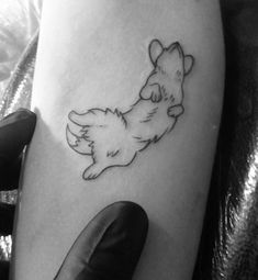 a small dog tattoo on the right thigh, with an outline of a puppy laying down