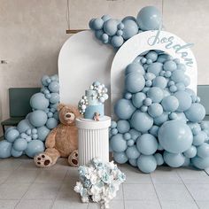 a teddy bear is sitting in front of some balloons and other decorations on the floor