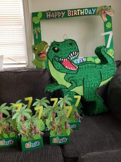 a green dinosaur birthday party with decorations and decorating on the couch in front of it