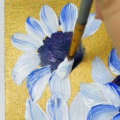 someone is painting flowers with blue and white paint