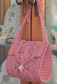 a pink crocheted purse hanging on a wooden door