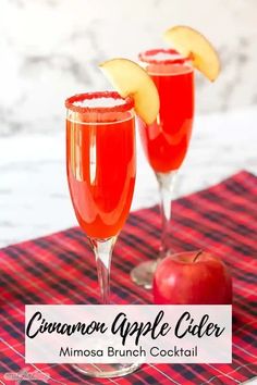 two glasses filled with apple cider sitting on top of a red checkered table cloth