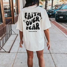 Introducing our "Faith Over Fear" Retro Letter Designed T-Shirt - a powerful and stylish expression of resilience and positivity. Embrace the vintage-inspired charm of this unique shirt, where timeless design meets a timeless message. Made from premium quality cotton, this shirt offers a comfortable fit and breathability, making it perfect for everyday wear. The soft fabric feels gentle against your skin, ensuring not only a fashionable statement but also a comfortable experience throughout the day. Whether you're navigating life's challenges or simply celebrating your unwavering faith, this T-shirt is a conversation starter and a symbol of strength.  Spread positivity and inspire those around you with the "Faith Over Fear" Retro Letter Designed T-Shirt. It's more than just clothing; it's Relaxed Fit Short Sleeve Shirt With Lettering, Inspirational Relaxed Fit Tops For Streetwear, Relaxed Fit Inspirational Shirt With Graphic Print, Inspirational Relaxed Fit Shirt With Graphic Print, Inspirational Graphic Print Shirt With Relaxed Fit, Inspirational Graphic Print Relaxed Fit Shirt, Inspirational Short Sleeve Shirt With Relaxed Fit, Inspirational Short Sleeve Relaxed Fit Shirt, Faith Over Fear Shirt