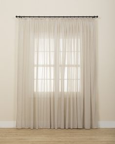 a white curtain hanging on the side of a wall next to a window with sheer curtains