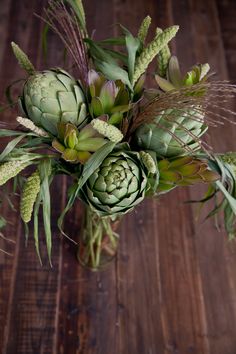 a vase filled with green flowers on top of a wooden table