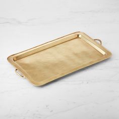 a gold tray with handles on a marble surface