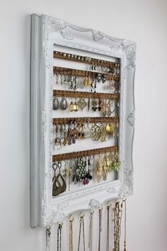 a wall mounted jewelry rack with several pairs of earrings hanging from it's sides