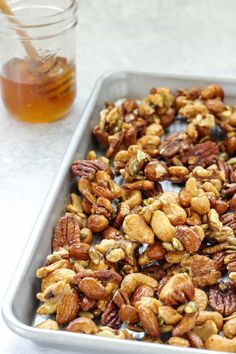 a pan filled with nuts next to a jar of honey