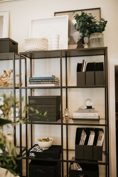 a bookshelf filled with lots of books next to a plant and pictures on the wall