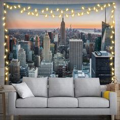 a couch sitting in front of a large cityscape with lights hanging from it's sides