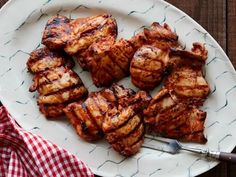 grilled meat on a white plate with a red and white checkered napkin