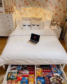 an open laptop computer sitting on top of a bed with lots of food in it