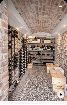 the wine cellar is stocked with many bottles and empty wooden boxes on shelves that are lined up against the brick wall