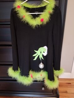 a black shirt with green fur trims and an image of a creature on it