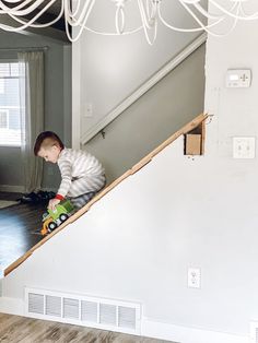 a young boy is playing on his skateboard at the bottom of stairs in an empty house