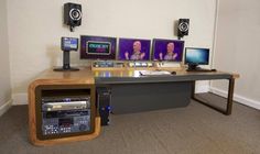 there is a desk with several monitors and speakers on top of it, along with other electronic equipment