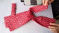 someone is making a red and white polka dot tie