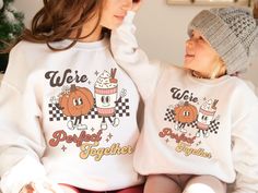 "Celebrate the magic of the fall season with our adorable Matching Mommy and Me Pumpkin Spice Fall Sweaters! Designed to capture the joy of togetherness, these sweaters feature the charming slogan \"We're a Perfect Match\" in a retro groovy font, accompanied by the cute graphic of a pumpkin and a pumpkin spice latte as retro mascot characters. If you're a fan of pumpkin spice lattes and love coordinating outfits with your little one, this Mommy And Me Fall collection is an absolute must-have. Whether it's for a Thanksgiving gathering or a casual day at the pumpkin patch, these Halloween Matching sweaters are sure to become your new fall favorites. These Pumpkin Sweatshirts are more than just a seasonal fashion statement; they represent the bond between mom and child. They make a delightful Playful Letter Print Sweater For Fall, Fun White Sweater For Fall, White Fun Sweater For Fall, Playful White Sweatshirt For Fall, Playful Letter Print Sweatshirt For Fall, White Family Matching Sweatshirt For Fall, Matching Cotton Sweatshirt For Fall, Family Matching Cotton Sweatshirt For Fall, Cotton Fall Sweatshirt