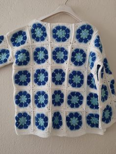 a blue and white crocheted sweater hanging on a wall