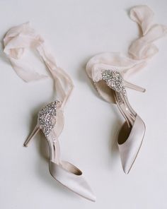 two pairs of wedding shoes on top of a white table