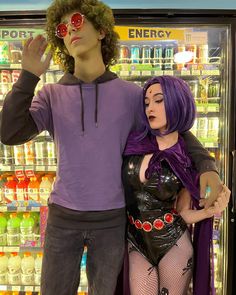 a man and woman dressed up in costumes standing next to an ice - cream display