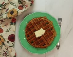 a green plate topped with a waffle covered in butter