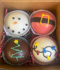 four decorated cupcakes in a cardboard box