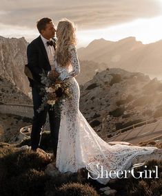 a bride and groom standing on top of a mountain