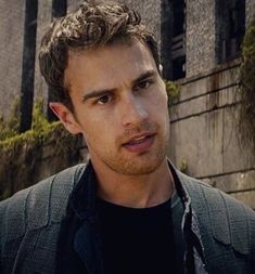 a man with curly hair standing in front of a building