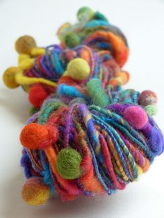 multicolored yarn with pom - poms on white surface