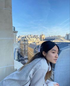 a woman standing on top of a roof next to a tall building with buildings in the background