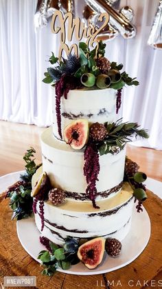 a wedding cake decorated with figs and greenery