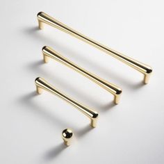 three brass handles and two knobs on a white surface