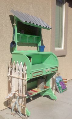 an old fashioned green painted desk on the side of a house