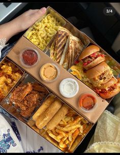 a person holding up a box filled with different types of food and condiments