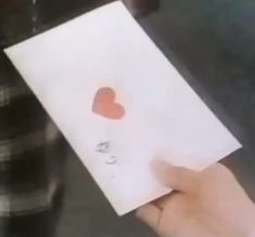 someone holding up a piece of paper with a heart on it