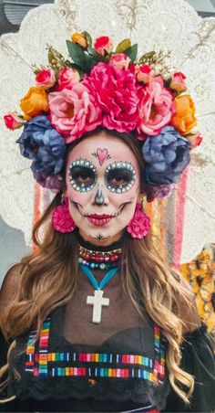 a woman with face paint and flowers on her head, wearing a flower wreath around her head