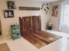 a bed made out of wooden boards in a room with pictures on the wall and floor