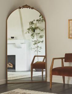 a mirror sitting on top of a wooden floor next to a chair and potted plant