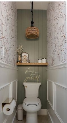 there is a toilet in the bathroom with wall paper on the walls and a basket hanging above it