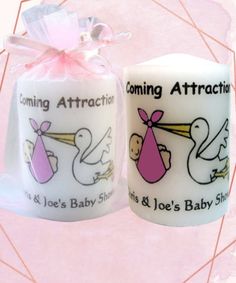 two candles with designs on them are next to a pink and white gift bag that says coming attraction