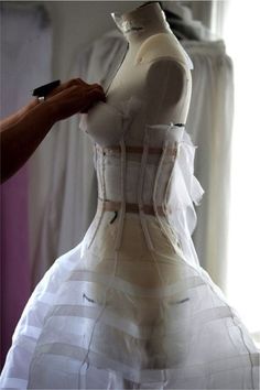 a mannequin being fitted into a white dress